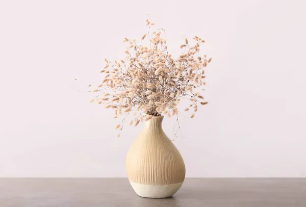 ライトウォールの近くのテーブルの上に美しい乾燥したスパイクを持つ花瓶 — ストック写真