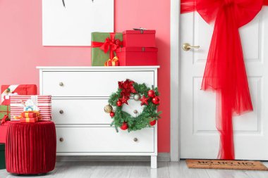 Renkli duvarın yanında Noel hediyeleri olan dekore edilmiş çekmeceler.