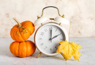 Alarm saati ve sonbahar yaprakları, arka planda bal kabakları. Gün ışığı kaydetme süresi bitti