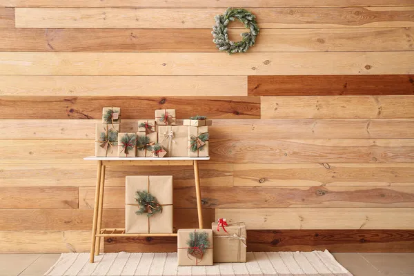 Stůl Vánoční Dárkové Krabice Jedlové Větve Blízkosti Dřevěné Zdi — Stock fotografie
