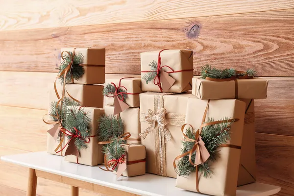 Стіл Різдвяними Подарунковими Коробками Ялиновими Гілками Біля Дерев Яної Стіни — стокове фото