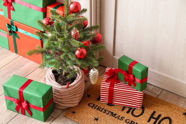 Kleine Kerstboom Met Geschenkdozen Bij Lichte Houten Deur — Stockfoto