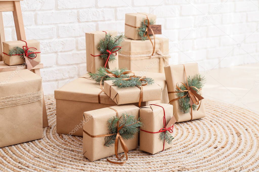 Christmas gift boxes with fir branches near white brick wall