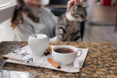 Kahve masasında bir fincan sıcak çay, gözlük ve müzik notaları.