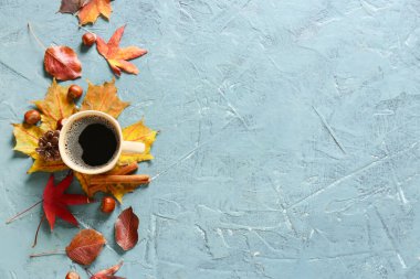 Sonbahar kompozisyonu, bir fincan kahve ve arka planda düşmüş yapraklar.