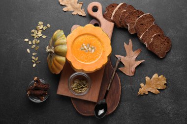 Balkabağında servis edilen lezzetli çorba ve siyah arka planda ekmek.