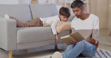 Evdeki küçük oğluna kitap okuyan bir adam.
