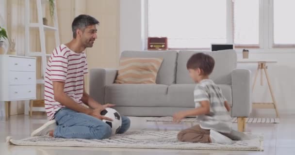 男と彼の小さな息子は家でボールと遊ぶ — ストック動画