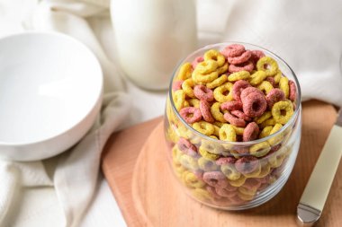 Masanın üzerinde gevrek mısır gevreği halkaları olan bir bardak.