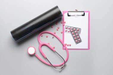 Steteskoplu röntgen taraması ve gri arka planda haplar.