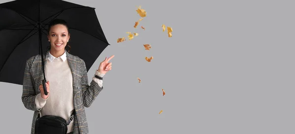 秋の服を着たスタイリッシュな若い女性とテキストのためのスペースとグレーの背景に傘 — ストック写真