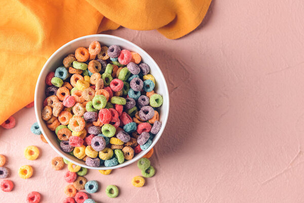 Bowl with crunchy corn flakes rings on color background