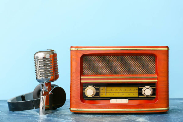 Retro radio receiver with microphone and headphones on color background