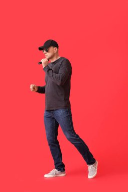 Kırmızı arka planda el feneri olan olgun bir adam.