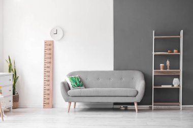 Oturma odasının içinde raf ünitesi, kanepe ve stadyum ölçer var.