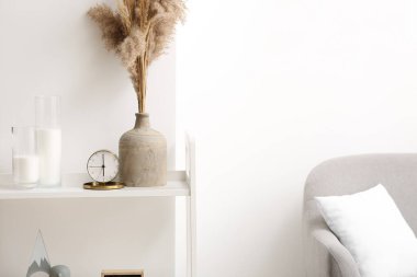 Şık bir kanepe ve oturma odasının içinde çalar saat olan bir raf.