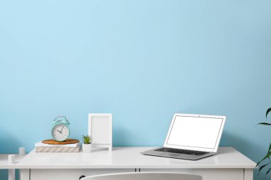 Odanın içinde alarm saati ve dizüstü bilgisayarı olan şık bir iş yeri