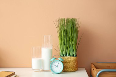 Çalar saat, mumlar ve çiçek renkli duvarın yanındaki masada.