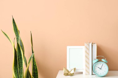 Çalar saat, kitaplar ve çerçeve renk duvarının yanında.