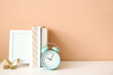 Çalar saat, kitaplar ve çerçeve renk duvarının yanında.