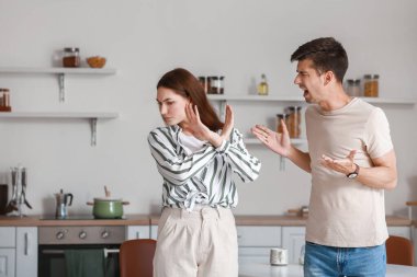Kızgın genç adam mutfakta karısına bağırıyor.