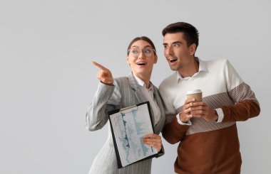 Gri arka planda iş arkadaşıyla dedikoduyu paylaşan genç bir kadın.