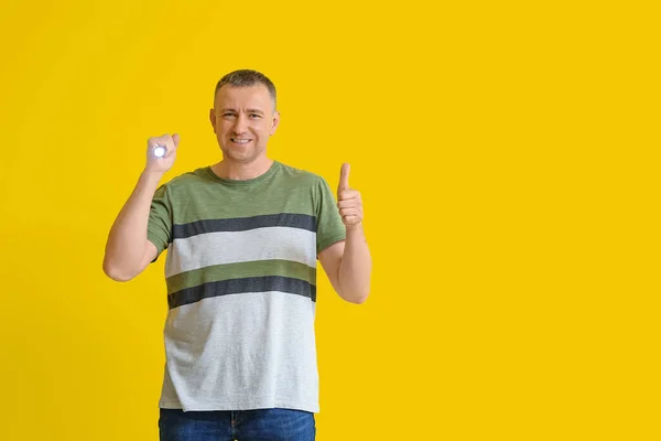 Mature Man Led Torch Showing Thumb Yellow Background — Stock Photo, Image