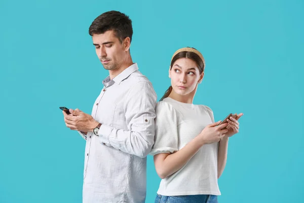 Geruzied Jong Paar Met Behulp Van Mobiele Telefoons Blauwe Achtergrond — Stockfoto