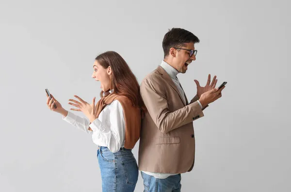 Boos Jong Paar Met Mobiele Telefoons Lichte Achtergrond — Stockfoto