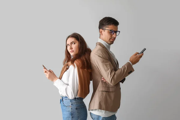 Quarreled Young Couple Using Mobile Phones Light Background — Stock Photo, Image