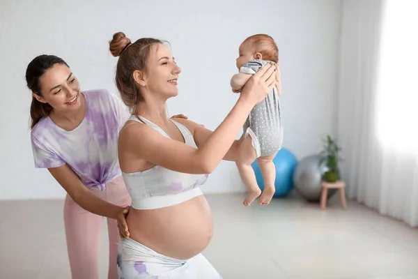 Genç Hamile Kadın Spor Salonunda Küçük Bebek Antrenörle Yoga Yapıyor — Stok fotoğraf