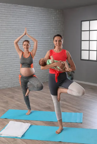 年轻孕妇带着教练和小宝宝在体育馆做瑜伽 — 图库照片