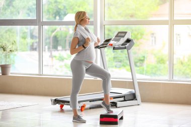 Genç hamile kadın spor salonunda aerobik yapıyor.