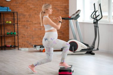 Genç hamile kadın spor salonunda aerobik yapıyor.