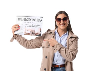 Güneş gözlüklü genç kadın beyaz arka planda gazeteye bakıyor.