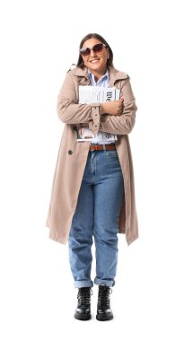 Beyaz arka planda gazetesi olan ceketli genç bir kadın.