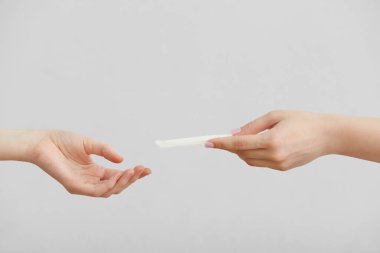 Beyaz arkaplanda adet pedi olan kadın elleri