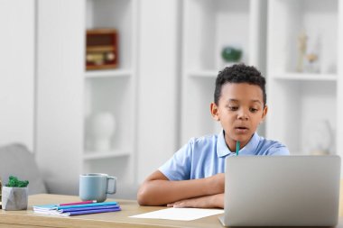 Küçük Afro-Amerikalı çocuk evde online çalışıyor.