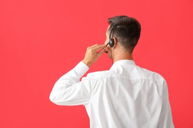 Kırmızı arka planda kulaklığı olan çağrı merkezinin erkek danışmanı