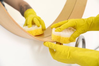 Evinde sünger temizleme aynası olan genç adam, yakın plan.