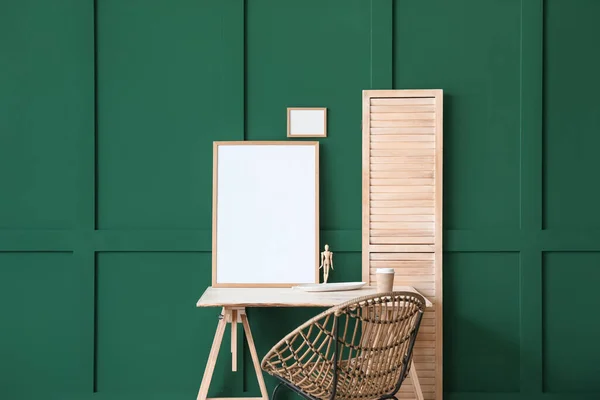木製のマネキンと緑の壁にぶら下がっている空白のフレームを持つ現代的な職場 — ストック写真
