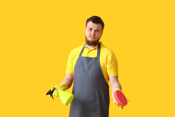 黄色の背景にスポンジと洗剤で若い男を動揺 — ストック写真