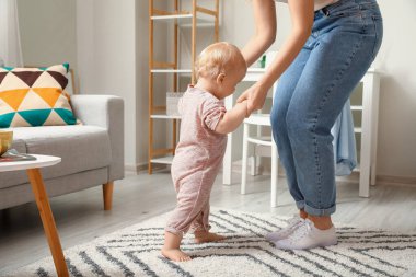Vücut kıyafetli şirin bir kız. Annesiyle evde yürümeyi öğreniyor.