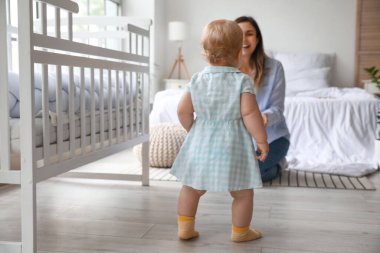 Çok tatlı bir bebek. Annesiyle yatak odasında yürümeyi öğreniyor.