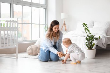 Anne yatak odasında küçük kızına oyuncak veriyor.