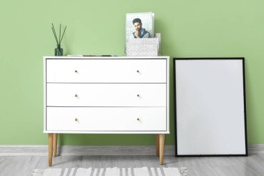 Sazlık dağıtıcı, şarjör ve yeşil duvarın yanındaki boş çerçeveli çekmeceler.