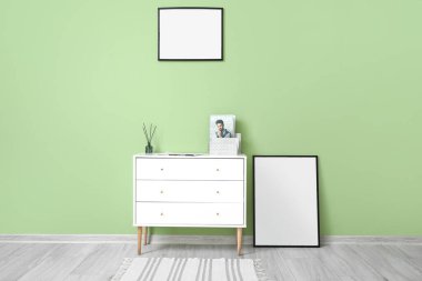 Yeşil duvarın yanında sazlık dağıtıcı bulunan boş çerçeveler ve çekmeceler.