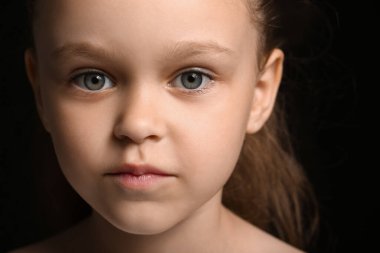 Siyah arka planda küçük güzel bir kızın portresi, yakın plan.