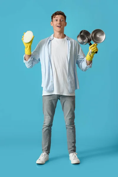 Jovem Surpreso Com Esponja Limpeza Panelas Cozinha Fundo Azul — Fotografia de Stock