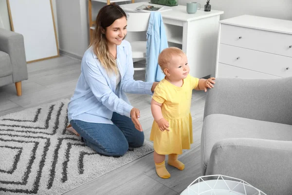 可愛いです赤ちゃん女の子で黄色ドレス学習へ歩くとともにお母さんとともにソファに家 — ストック写真